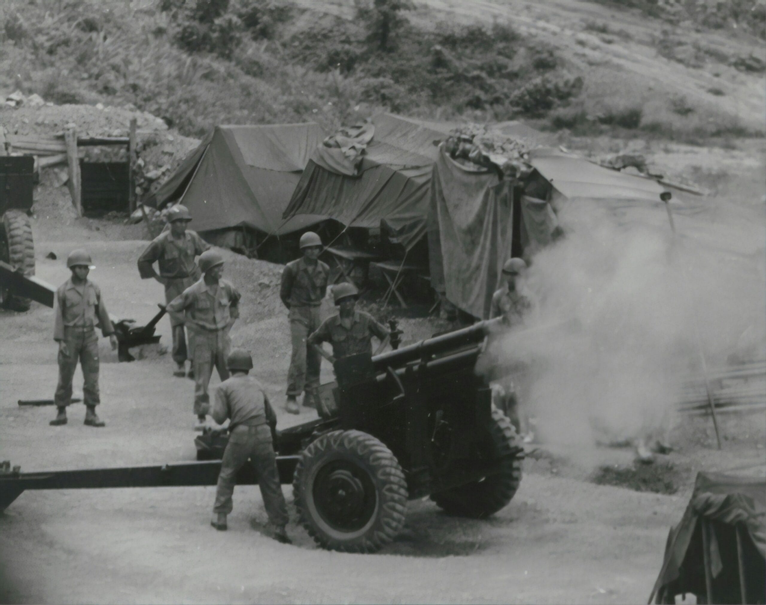 Soldados operando artillería en un campamento durante un conflicto bélico, foto de archivo.